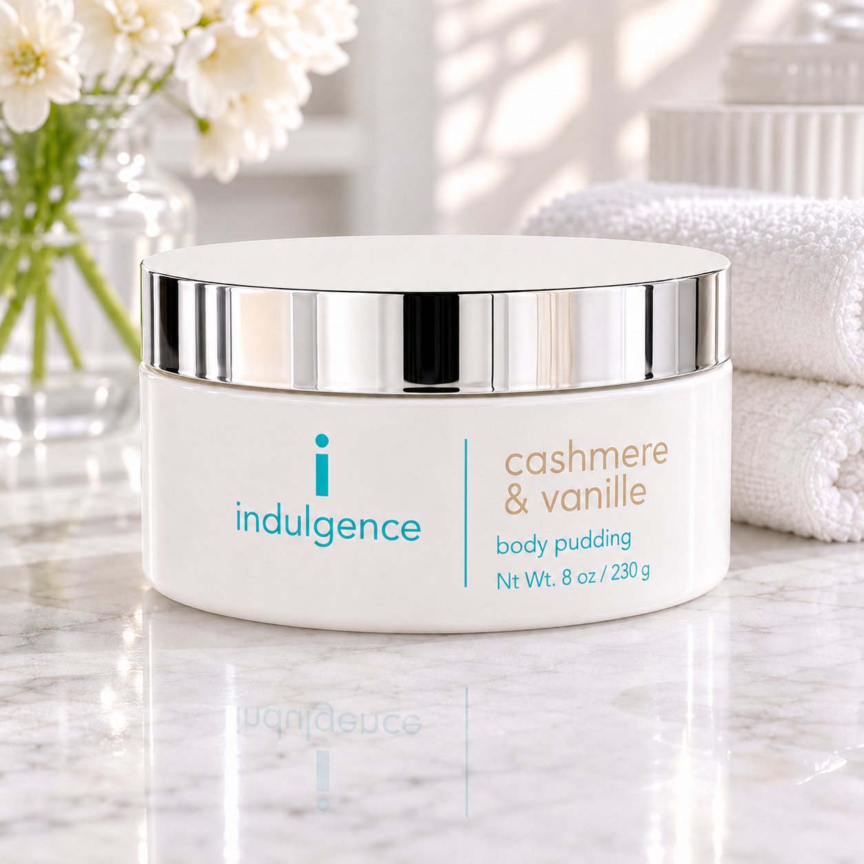 Indulgence cashmere & vanille body pudding container on a marble surface with flowers in the background