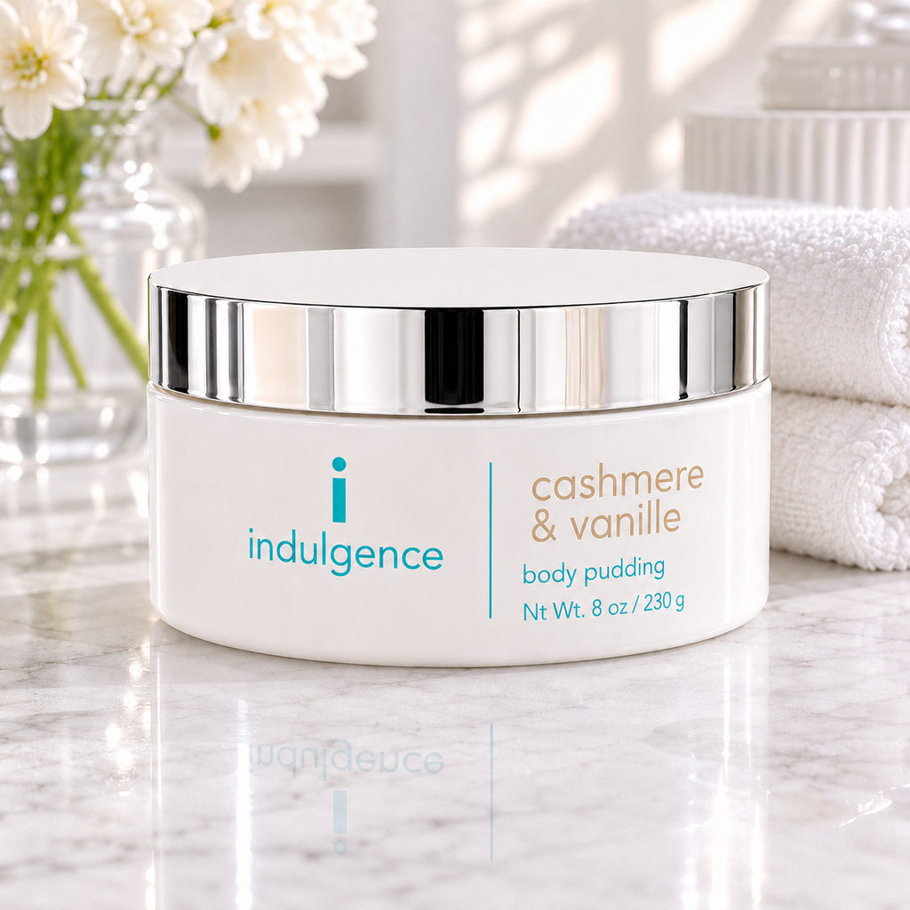 Indulgence cashmere & vanille body pudding container on a marble surface with flowers in the background