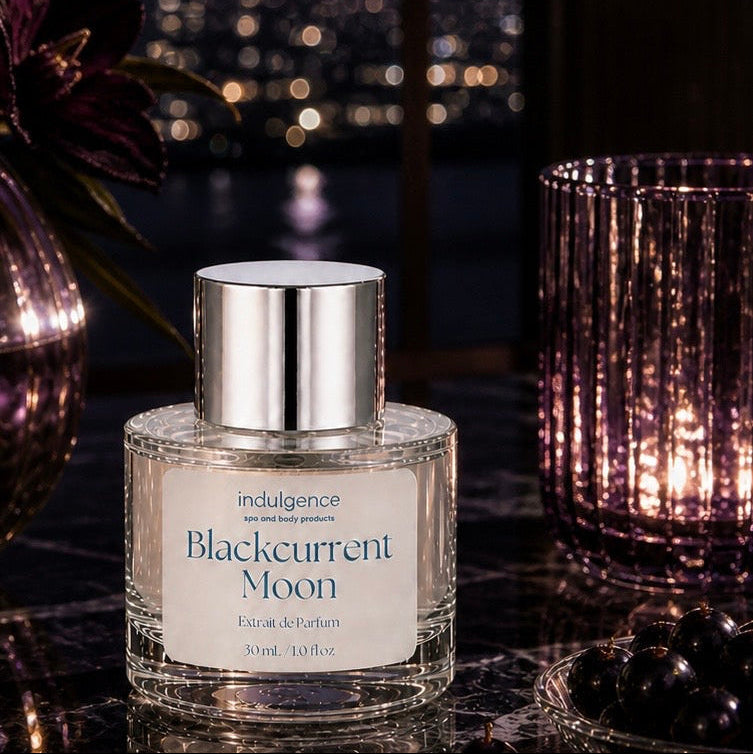 Perfume bottle labeled 'Blackcurrant Moon' on a reflective surface with a night cityscape in the background.